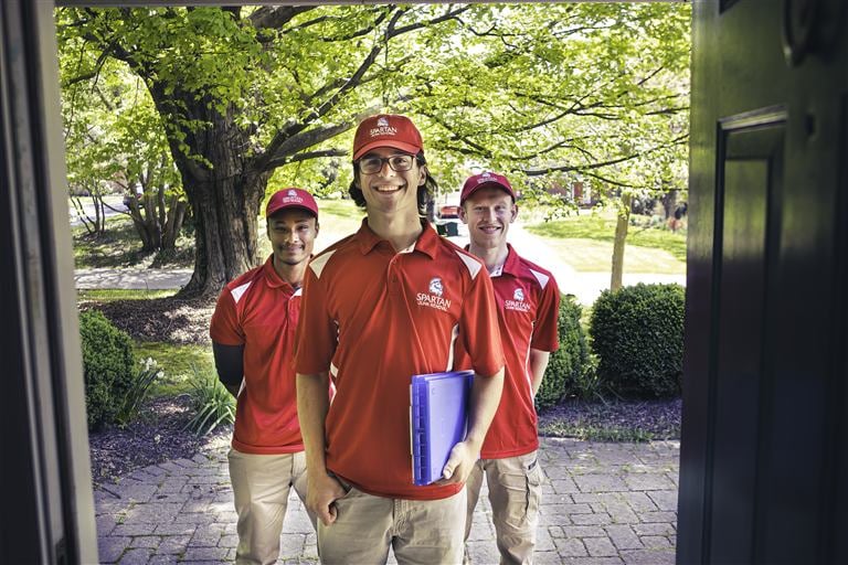 Spartan Junk Removal crew in red Spartan shirts and caps, ready to work at a Maryland home.